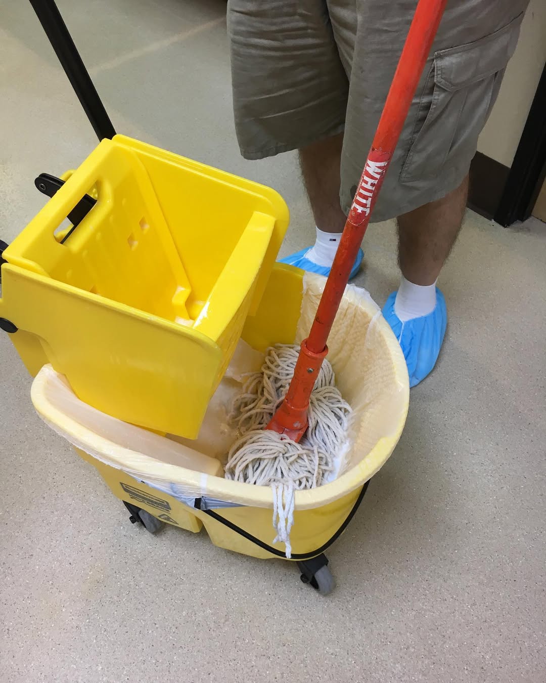 MGD technician mopping a clinic floor with PPE shoe covers
